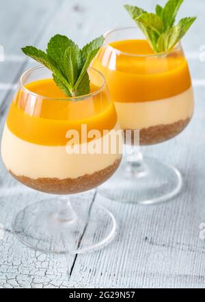 Cheesecake di Mango guarnito con menta servita nei bicchieri Foto Stock
