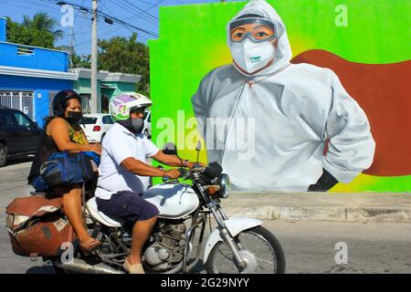 La gente su una motocicletta passa davanti al murale che celebra gli operatori sanitari come Covid-19 Heroes, Merida Messico Foto Stock