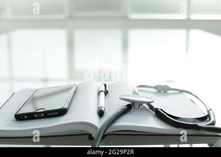 Telefono diario penna e stetoscopio su tavolo di vetro Foto Stock