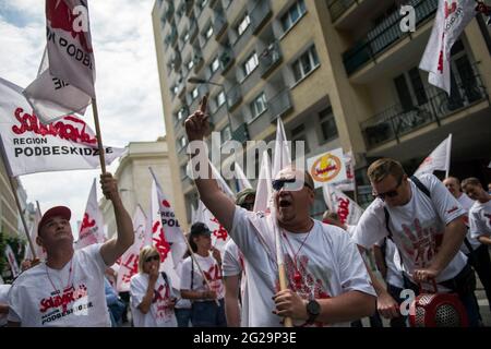 Un manifestante che gestiva e agitava la bandiera di Solidarnosc (solidarietà) durante la manifestazione.migliaia di lavoratori polacchi dell'industria estrattiva del carbone e dell'energia protestavano a Varsavia contro la graduale eliminazione dell'uso del carbone e contro un ordine della Corte dell'Unione europea di chiudere immediatamente la miniera di carbone marrone Turow - la sentenza è stata In risposta ad una causa della vicina Repubblica ceca che dice che la miniera sta drenando acqua dai suoi villaggi di confine. La protesta è stata organizzata dal sindacato indipendente "Sollidarnosc" (solidarietà). Foto Stock