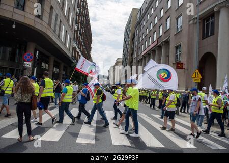 I manifestanti stanno sventolando le bandiere di Solidarnosc (solidarietà) mentre attraversano la strada, Durante la dimostrazione.migliaia di lavoratori polacchi dell'industria carboniera ed energetica hanno protestato a Varsavia contro la graduale eliminazione dell'uso del carbone e contro un'ordinanza della Corte dell'Unione europea di chiudere immediatamente la miniera di carbone marrone Turow - la sentenza è stata in risposta ad una causa del vicino ceco Repubblica che dice che la miniera sta drenando acqua dai suoi villaggi di confine. La protesta è stata organizzata dal sindacato indipendente "Sollidarnosc" (solidarietà). Foto Stock