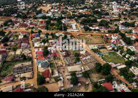 Vista sul drone delle case di sabbia con il verde e le strade polverose durante il giorno d'estate in Gambia, Africa Foto Stock