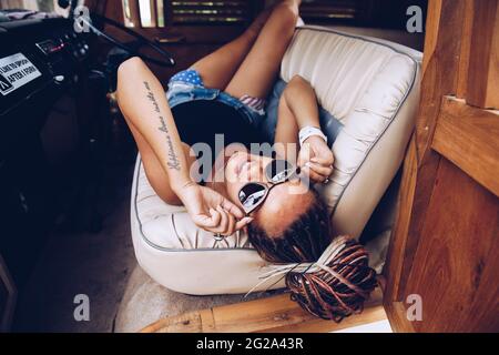 Donna sorridente sdraiata in un furgone d'epoca sulla strada Foto Stock