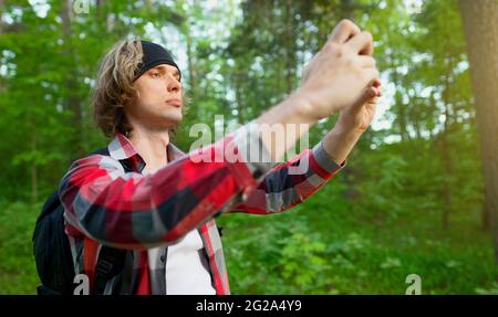 Uomo che fa selfie con smartphone nella foresta. Foto Stock