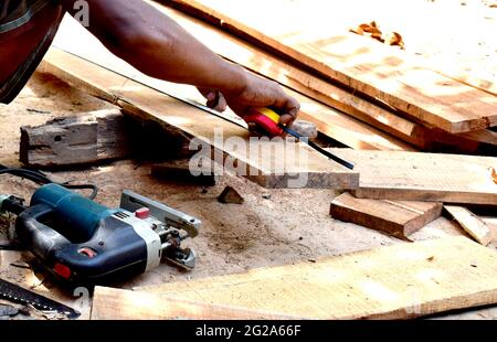 carpentiere uomo caucasico utilizzando il nastro di misurazione guardando dimensione di legno a workspace. professione artigiana in fabbrica di legno. Foto Stock