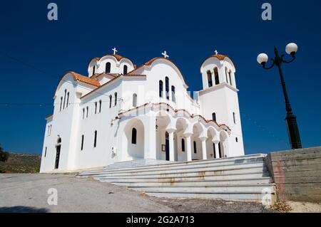 una chiesa bianca greca contro cielo blu con lampione Foto Stock