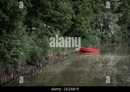 barca a remi rossa in un piccolo fiume Foto Stock