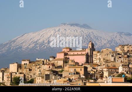 Vista della città rurale della Sicilia, sullo sfondo il vulcano innevato Etna, Italia Foto Stock