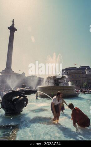 Estate nella città di Londra: I bambini si divertono, rinfrescarsi nella fontana di Trafalgar Square. Foto Stock