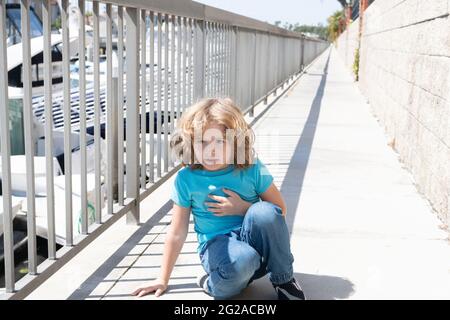 Pausa respiro. Ragazzo relax hunkering giù sul lungomare. Bambino ragazzo prendere riposo breve Foto Stock
