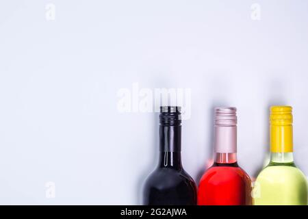 Bottiglie di vino rosso, rosa e bianco su tavola bianca. Vista dall'alto con spazio per la copia Foto Stock