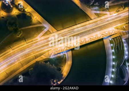 moderno ponte cittadino su un fiume illuminato di notte. foto aerea, vista dall'alto. Foto Stock