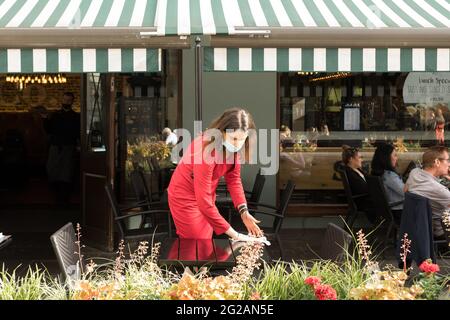 Londra, Regno Unito. 7 Giugno 2021. Una cameriera pulisce un tavolo in un bar ristorante a Soho, Londra.mentre il governo britannico ha revocato le restrizioni imposte sui servizi di ristorazione in relazione al COVID, la folla di persone ha inondato ristoranti, bar e pub in tutto il centro di Londra durante il fine settimana per prendere un drink. I ristoranti stanno facendo del loro meglio per garantire un'igiene all'interno dei loro locali e stanno ancora adottando misure per mantenere una distanza sicura da mangiare tra i tavoli. Si vede che la gente è molto entusiasta della riapertura a Londra. Credit: Belinda Jiao/SOPA Images/ZUMA Wire/Alamy Live News Foto Stock