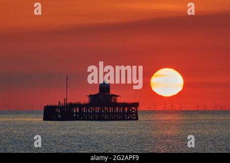 Herne Bay, Kent, Regno Unito. 10 Giugno 2021: Tempo Regno Unito. Il sole sorge all'inizio di un'altra giornata calda e soleggiata vicino alla testa del molo in rovina a Herne Bay, che è stata distrutta da tempeste nel 1978 e abbandonata. L'impianto eolico di Londra si trova all'orizzonte. Il clima caldo è impostato per continuare fino alla prossima settimana. Credit: Alan Payton/Alamy Live News Foto Stock