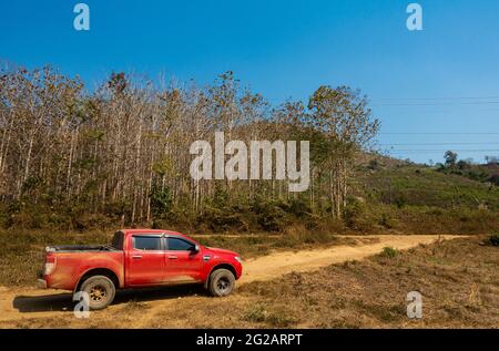 Veicolo 4x4 rosso, sporco di polvere, su strada sterrata nel mezzo di nessuna zona nella zona rurale dell'entroterra. Foto Stock