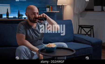 Giocatore professionista sconvolto seduto di fronte alla televisione perdendo video giochi di calcio con controller wireless, joystick. Uomo frustrato per il gioco sopra il dressing in pajama rilassante giocando la concorrenza in linea Foto Stock