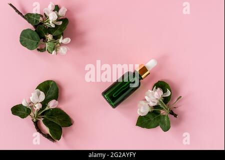 Spa biologica cosmetica con ingredienti di erbe. Siero con estratti di erbe per la pelle. Cosmetici naturali in bottiglia di vetro con una pipetta e la mela flowe Foto Stock