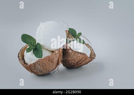 Porzione di gelato servita in noci di cocco con foglie di menta. Foto Stock