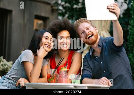 Amici che si divertono in un caffè, sorridendo e bevendo cocktail insieme. Foto Stock