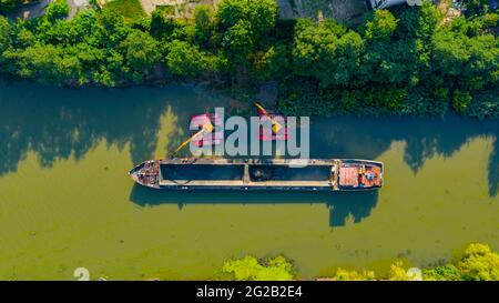 Vista dall'alto su due escavatori che si dredgono mentre dragano, lavorando su fiume, canale, profondità e rimozione di sedimenti, fango dal letto del fiume in una wa inquinata Foto Stock