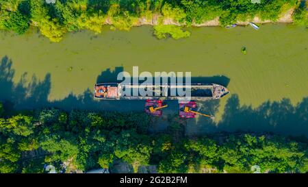 Vista dall'alto su due escavatori che si dredgono mentre dragano, lavorando su fiume, canale, profondità e rimozione di sedimenti, fango dal letto del fiume in una wa inquinata Foto Stock