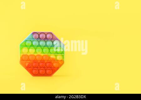 Nuovo giocattolo alla moda popolare silicone colorato anti stress Pop it per bambini su sfondo giallo. Spazio di copia. Premere Bubble pop. Foto Stock