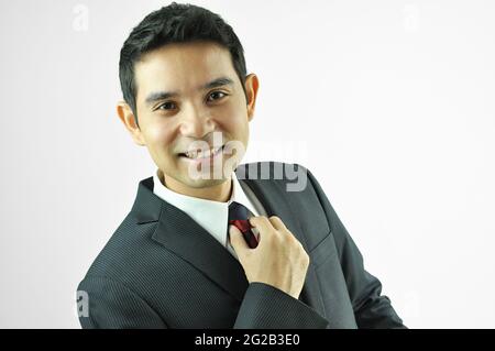 Uomo d'affari sorridente che ha riposto la nuca Foto Stock