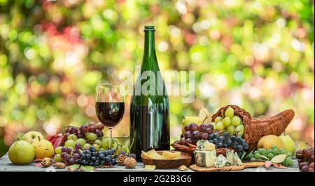 Uva, bottiglia di vino e formaggi diversi su tavola di legno di campagna e sfocato sfondo colorato autunno. Varietà di prodotti come il simbolo di autu Foto Stock