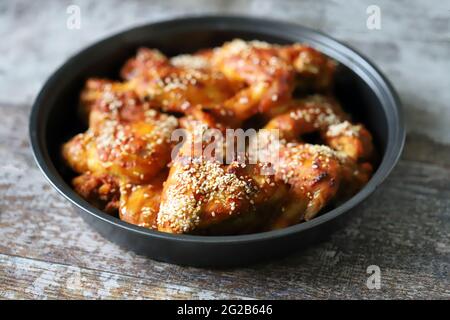 Ali di pollo al forno con semi di sesamo in una padella. Cibo spazzatura. Deliziose ali di bufalo. Foto Stock