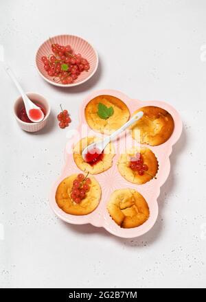 Deliziosi mini dolci freschi con ribes rosa e marmellata in una padella di muffin in ceramica. Spazio di copia. Foto Stock