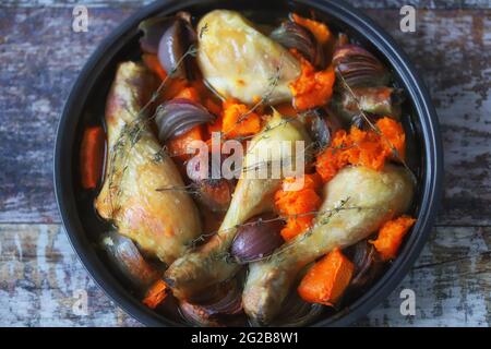 Cosce di pollo cotte con zucca e cipolle blu in una padella. Delizioso pranzo sano. Foto Stock