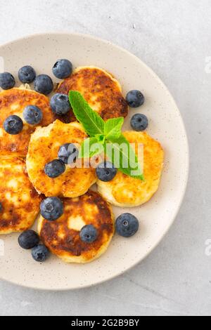 Torta al formaggio Cottage con mirtilli e menta in un piatto su sfondo grigio Foto Stock