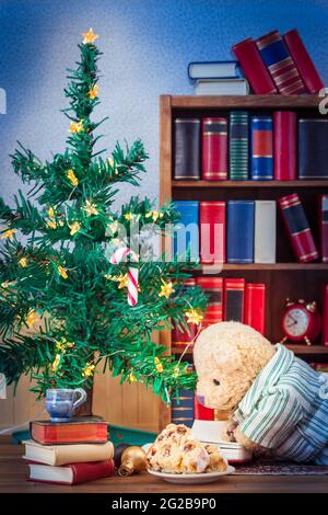 Libri lettura orsacchiotto sul pavimento casa con dolce torta indossare pajama sotto albero di natale Foto Stock