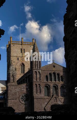 Resti di una finestra in rovina nel Palazzo Vescovile del 14th ° secolo accanto alla Cattedrale di San Davide a Pembrokeshire, Galles, Regno Unito, incornicia la torre centrale della cattedrale e il suo fronte ovest, Ricostruito in arenaria viola in stili misti e con standard tecnici scadenti nel 1793 dal celebre architetto neoclassico Regency e Georgiano John Nash. Progettò Buckingham Palace, Marble Arch e Regent Street di Londra, e anche il Royal Pavilion di Brighton, ma la facciata dovette essere rimodellata negli anni '1860s quando iniziò a sporgere verso l'esterno e necessitò di ulteriori riparazioni importanti negli anni '1990s. Foto Stock