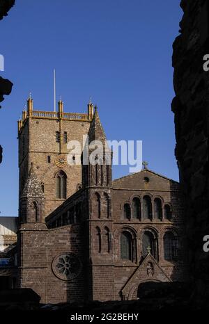 I bordi macabri di una finestra in rovina nel Palazzo Vescovile del 14th ° secolo accanto alla Cattedrale di St Davids a Pembrokeshire, Galles, Regno Unito, incorniciano la torre centrale della cattedrale e il suo fronte ovest, Ricostruito in arenaria viola in stili misti e con standard tecnici insoddisfacenti nel 1793 dal celebre architetto neoclassico Regency e Georgiano John Nash, designer di Buckingham Palace, Marble Arch e Regent Street di Londra, e dal Royal Pavilion di Brighton. La facciata doveva essere rimodellata negli anni '1860s, quando iniziò a piegarsi verso l'esterno e necessitò di ulteriori riparazioni importanti negli anni '1990s. Foto Stock