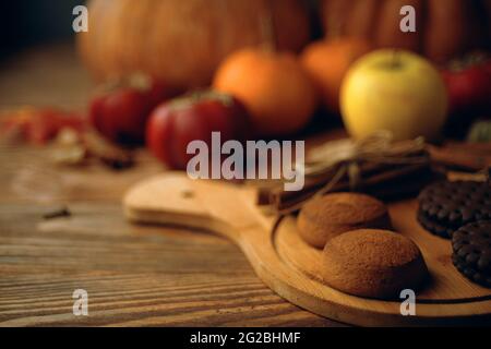 Biscotti al cioccolato su vassoio, zucche, persimmons e mele sullo sfondo. Vendemmia autunnale su tavola di legno. Il concetto di Ringraziamento e Halloween. Foto Stock