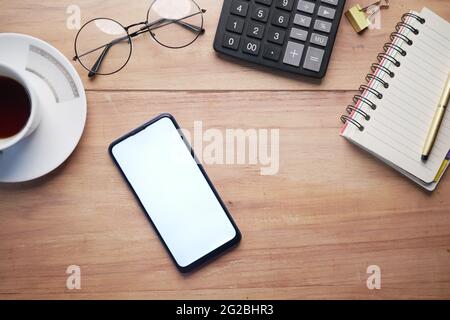 vista dall'alto di smartphone, calcolatrice e blocco note sul tavolo Foto Stock