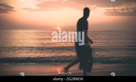 Uomo Walking Beach Tramonto Foto Stock