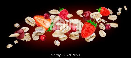 Flying fiocchi di avena con frutti di bosco isolato su sfondo nero. La caduta di avena Foto Stock