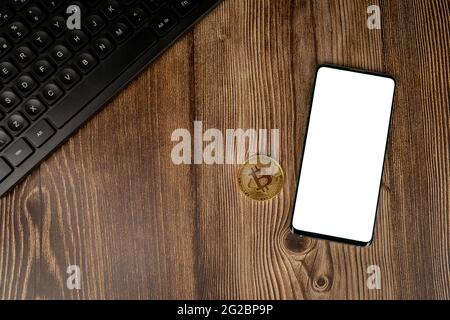 Smartphone con mockup bianco sullo schermo e moneta bitcoin criptovaluta con tastiera nera su sfondo in legno con spazio per la copia. Modello Foto Stock