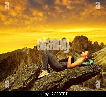 Turista sdraiato su una roccia nelle Dolomiti al tramonto, Alpi Italien. Foto Stock