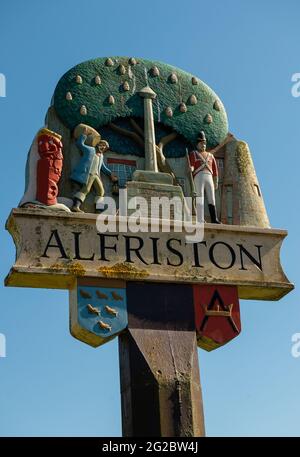 Alfriston, East Sussex, Regno Unito. 5 giugno 2021. Vista ad angolo basso del cartello del villaggio di Alfriston, contro un cielo blu chiaro. Foto Stock