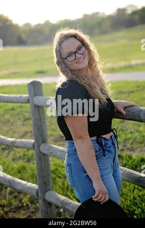 Bella ragazza capelli biondo che indossa camicia nera e jeans Foto Stock