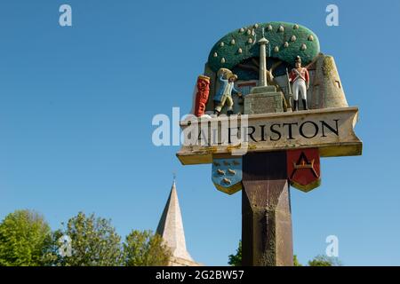 Alfriston, East Sussex, Regno Unito. 5 giugno 2021. Vista ad angolo basso del cartello del villaggio di Alfriston, contro un cielo blu chiaro. Foto Stock