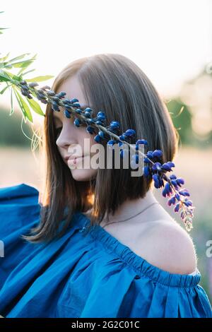 Bella ragazza copre la sua faccia con un fiore lupino. Primo piano. Foto estate. Foto Stock