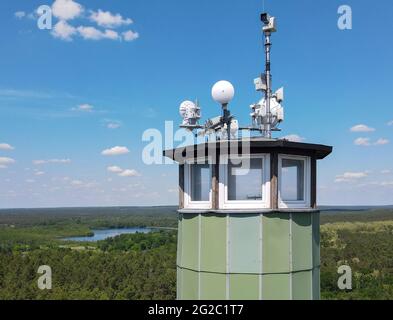 09 giugno 2021, Brandeburgo, Zesch am See: La tecnologia radio e una telecamera sono montate sul tetto della torre di avvistamento incendi 'Zesch' vicino a Wünsdorf presso l'Ufficio forestale del Brandeburgo (vista aerea con un drone). Con l'aumento delle temperature, il pericolo di incendi boschivi è aumentato nel Brandeburgo. Due centri di incendi boschivi a Wünsdorf (Teltow-Fläming) e Eberswalde (Barnim) controllano ciò che sta accadendo nello stato. Il personale è stato assegnato dalla fase 3. Foto: Patrick Pleul/dpa-Zentralbild/ZB Foto Stock