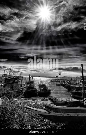 Fotografia di paesaggi in bianco e nero di barche contro il cielo drammatico con raggi solari penetranti. Thailandia Sud-est asiatico Foto Stock