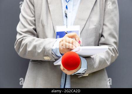 Giornalista femminile a conferenza stampa o evento mediatico, scrivendo note, tenendo il microfono. Concetto di giornalismo broadcast. Foto Stock