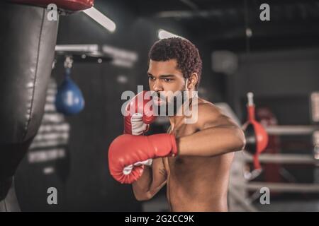 Giovane kickboxer dalla pelle scura che si allena in palestra Foto Stock