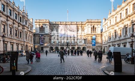 La Royal Academy of Arts, Londra. Visitatori nel cortile centrale della RA con manifesti per Anthony Gormley e Lucian Freud visibili. Foto Stock